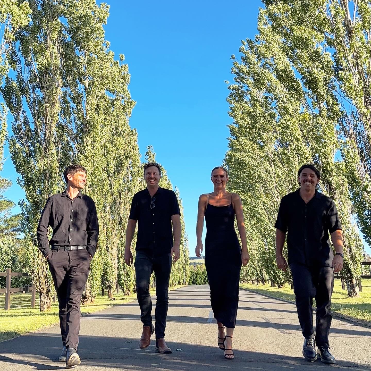 Blue Vinyl 4-piece walking down a tree-lined avenue at a vineyard venue