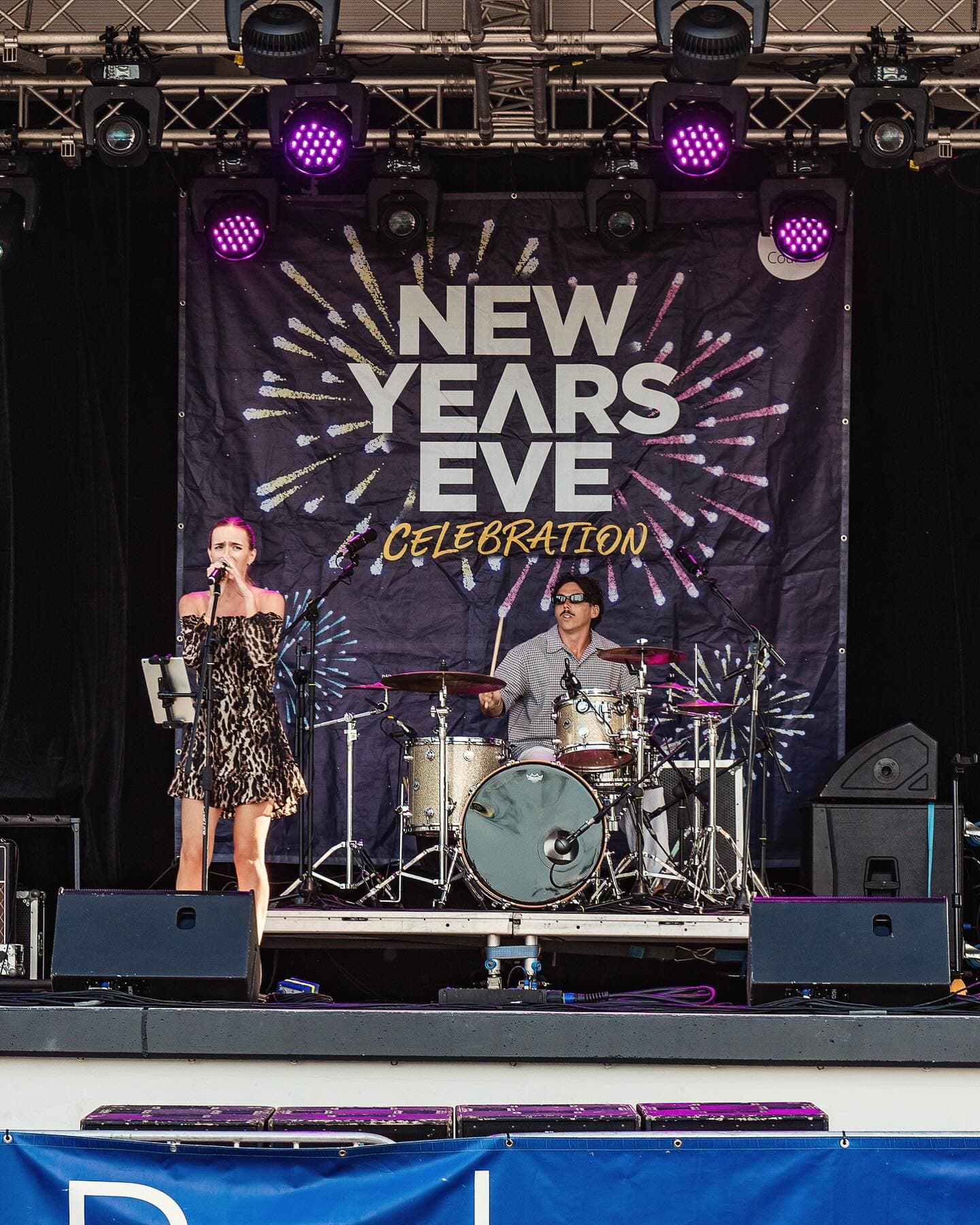 Blue Vinyl vocalist and drummer performing on the main stage at a New Year's Eve event